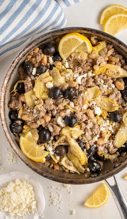 A skillet with ground turkey, black olives, beans, artichoke hearts, and feta cheese.