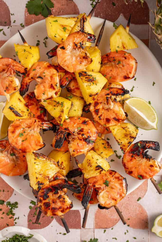 A plate with grilled pineapple shrimp skewers.