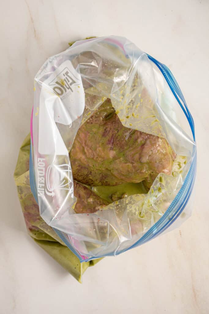 An open zip top bag with steak and marinade.