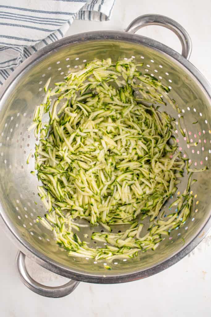 Shredded zucchini in a colander.