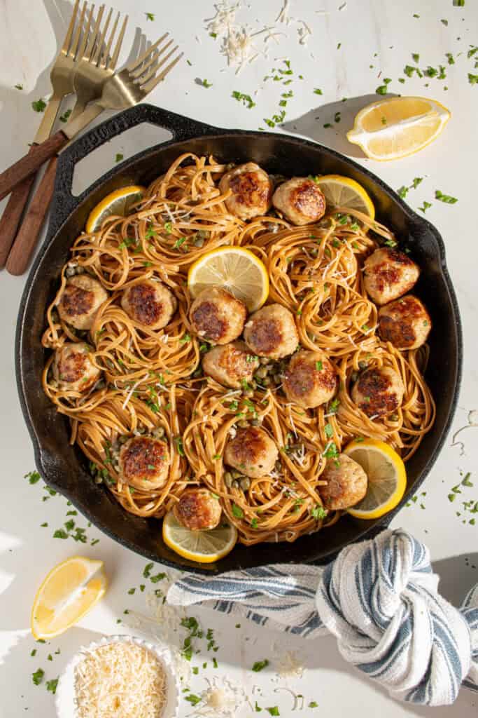 A skillet full of pasta and chicken piccata meatballs.