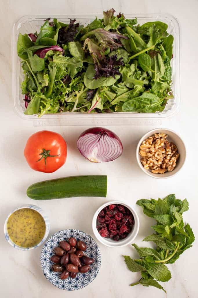 Ingredients for a spring mix salad laid out on a tabletop.