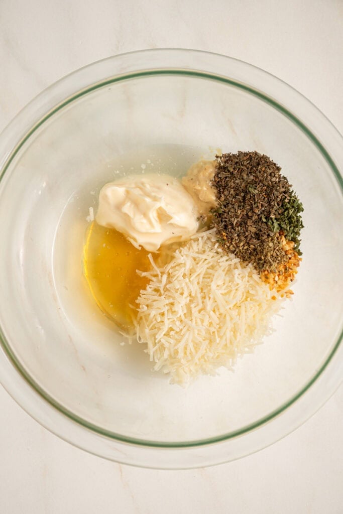 A bowl with lemon juice and vinegar and seasonings for making Italian Dressing.