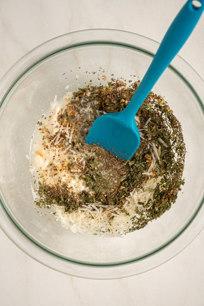 Everything but the olive oil being mixed together in a bowl to make Italian Dressing.